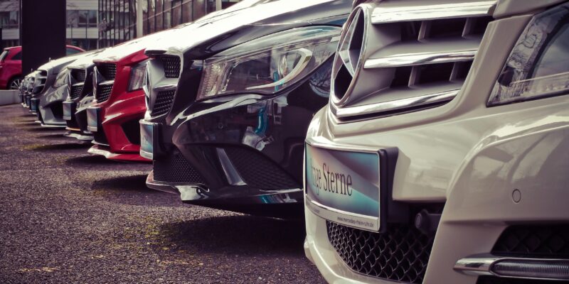 Luxury cars lined up at an outdoor dealership, showcasing sleek designs.
