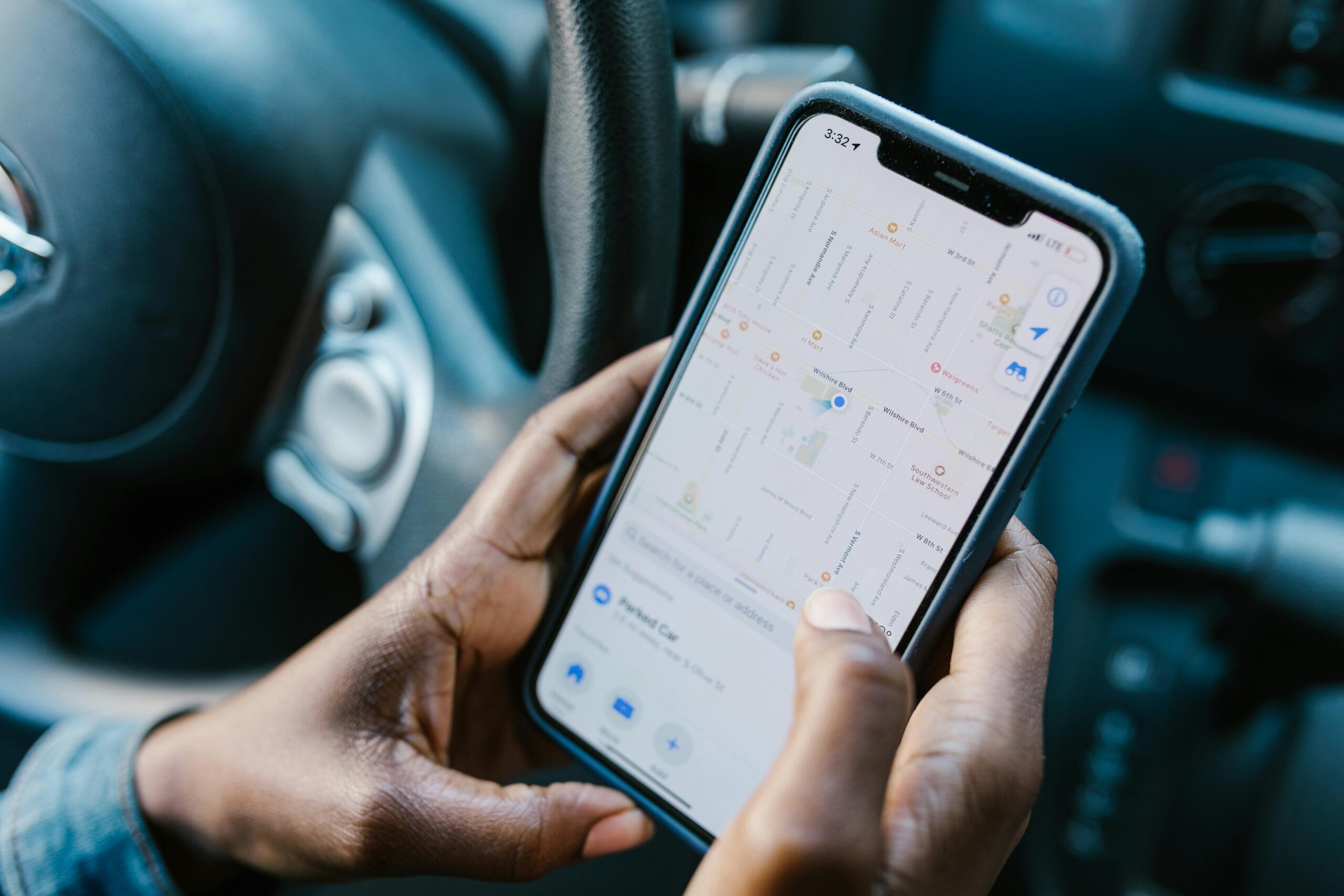 pexels-photo-7362886-7362886 Close-up of hands holding a smartphone with GPS navigation displayed, in a car setting.
