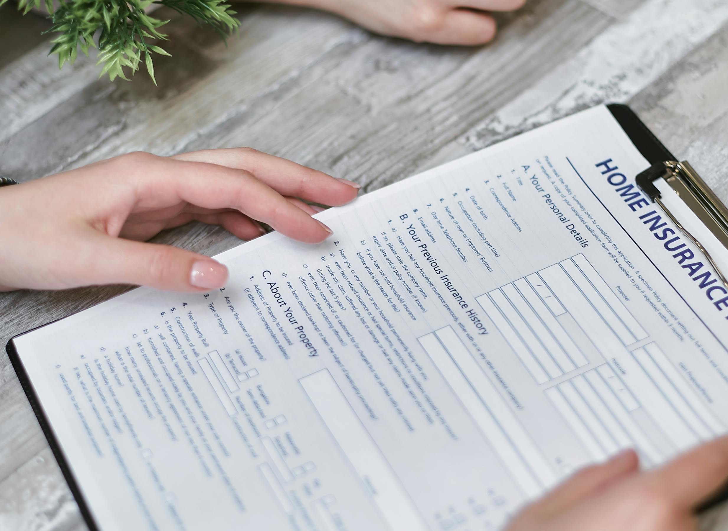 pexels-photo-7731332-7731332 Close-up of hands holding a home insurance document indoors, showing personal details section.