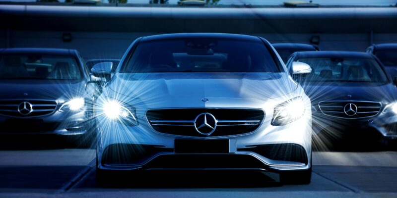Front view of a lineup of Mercedes-Benz cars with bright headlights, showcasing luxury and elegance.